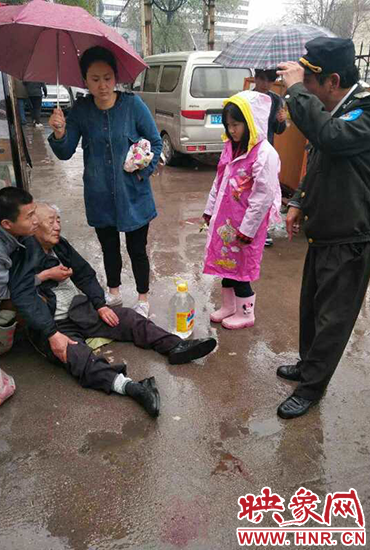 女孩為倒地老人撐傘。