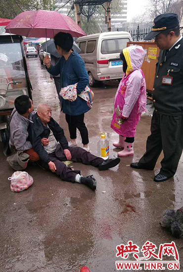 女孩為倒地老人撐傘。