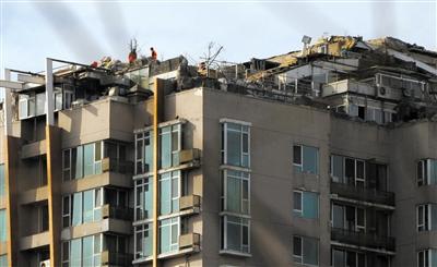 　　昨日，身穿橘黃色馬甲的工作人員在人濟(jì)山莊樓頂拆除違章建筑。新京報(bào)記者 吳江 攝