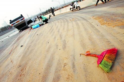 被撞的環(huán)衛(wèi)工躺在地上，身上蓋著藍(lán)色布?jí)K，現(xiàn)場除散落的汽車碎片外，還留有被撞斷的掃帚。