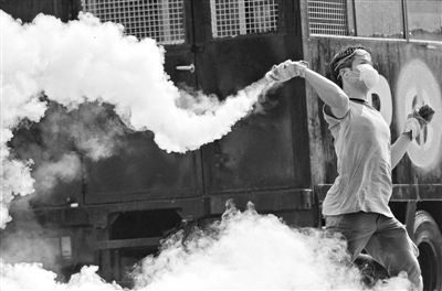 12月2日，泰國曼谷，一名反政府示威者在總理府附近向負(fù)責(zé)執(zhí)勤的警察投擲催淚彈。英拉請(qǐng)求示威者不要再試圖占領(lǐng)政府工作部門，不要逼迫政府工作人員選邊站。