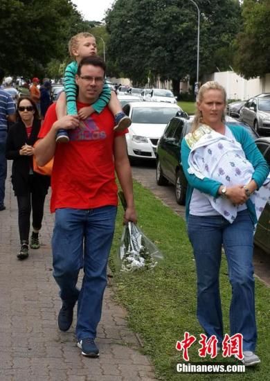 圖為一個(gè)白人家庭，由父母帶著孩子到曼德拉家門外悼念。中新社發(fā) 宋方燦 攝