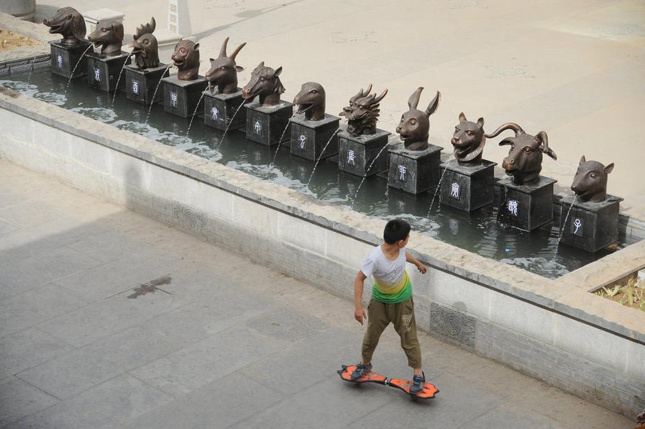 圖為一名市民從獸首旁經(jīng)過。