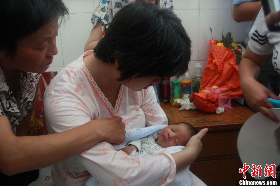 圖為久別重逢，獲救嬰兒母親悉心撫摸愛子。張一辰 攝