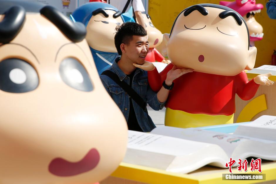4月22日，游客與蠟筆小新合影?！跋灩P小新25周年紀(jì)念特展”日前在北京開(kāi)展，吸引了不少市民游客。