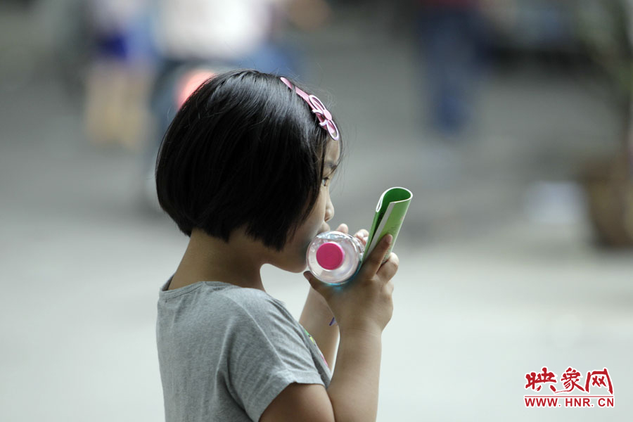 6月7日，鄭州回中考點(diǎn)，一名孩子拿著一瓶礦泉水，等待哥哥走出考場(chǎng)