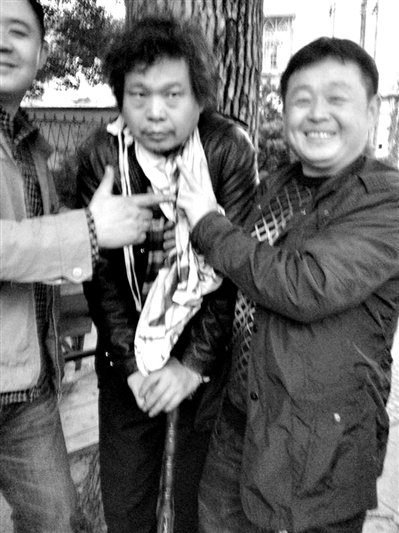 兩名接訪人員與患有癌癥的訪民段新德合影時，面帶笑容擺出勝利的手勢。