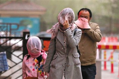 昨日下午，朝陽區(qū)豆各莊，行人將紗巾裹在頭上防沙塵。