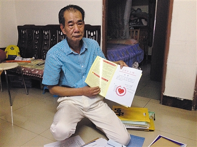 翻出一家網(wǎng)站贈予的“中國好人”證書，區(qū)少坤單膝跪在地上，“你看，我是中國好人啊?！?范春旭 攝