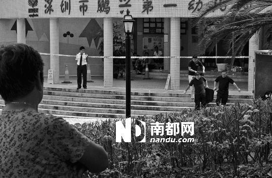 →7月19日，鵬興花園第一幼兒園門前，民警在現(xiàn)場(chǎng)進(jìn)行完勘查取證后，園長(zhǎng)和保安的尸體被運(yùn)走。南都記者 徐文閣 攝