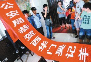 面對警方收繳的條幅，老板楊某也不好意思地用手遮擋臉