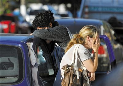 27日，遇難者親友在火災(zāi)現(xiàn)場旁哭泣。