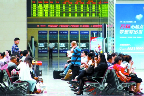 候車大廳溫度很高，一名乘客一手扇風、一手擦汗