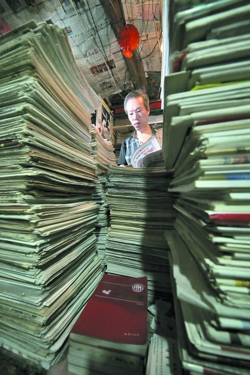 王曉民坐在寫字桌前，被報紙淹沒。
