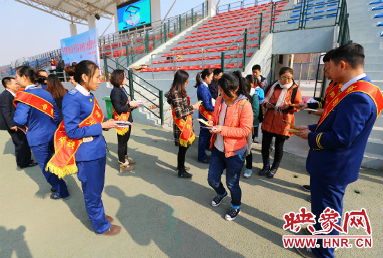 活動現(xiàn)場工作人員給同學(xué)們發(fā)放宣傳冊、環(huán)保袋。