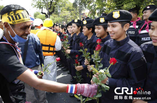 2013年12月03日,曼谷總理府與曼谷警署允許反政府示威民眾進(jìn)入,雙方進(jìn)入暫時“停戰(zhàn)”狀態(tài)迎接泰王生日。曼谷警察總署,女警們手持鮮花送給反政府示威民眾。圖片來源:Manish Swarup/東方IC