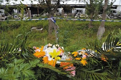 昨日，吉林省德惠市吉林寶源豐禽業(yè)有限公司燃燒事故現(xiàn)場(chǎng)警戒線外，遇難者家屬在路邊擺放了花圈祭奠逝去的親人。吳江 攝