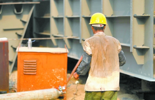 工地上，一建筑工人的衣服被汗水浸透。