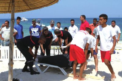 6月26日，在突尼斯蘇塞，救生員和醫(yī)務(wù)人員在發(fā)生襲擊事件的海灘運(yùn)送一名死者的遺體。新華社發(fā)