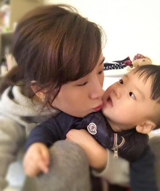 照片中李念狂吻兒子，小寶貝自顧自地玩著。