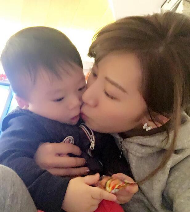 照片中李念狂吻兒子，小寶貝自顧自地玩著。