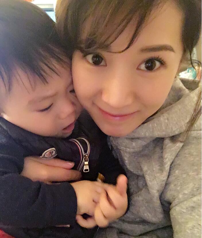 照片中李念狂吻兒子，小寶貝自顧自地玩著。