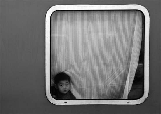 一個孩子把頭伸向窗外，他想再看送別的親人一眼