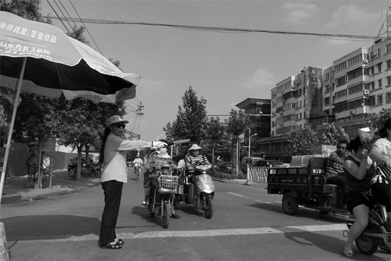 昨日，開封市區(qū)一名協(xié)管員在指揮群眾過馬路