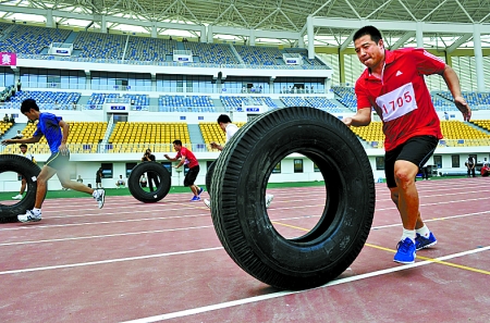 8月15日，運(yùn)動員們正在進(jìn)行推輪胎賽跑。