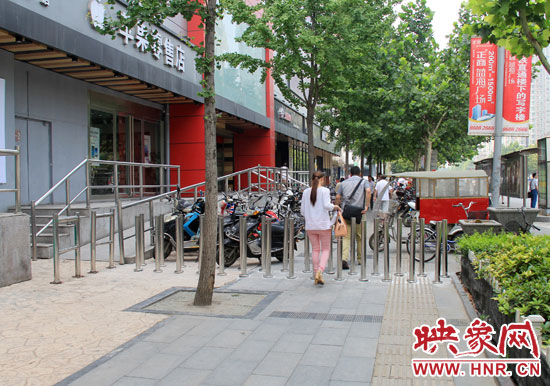 圖中道路左側的無障礙通道被鋼管隔離,右側的盲道也被侵占。