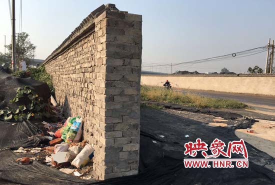 一墻之隔，一邊是道路，一邊是垃圾和荒草，市民質(zhì)疑其為遮羞墻。