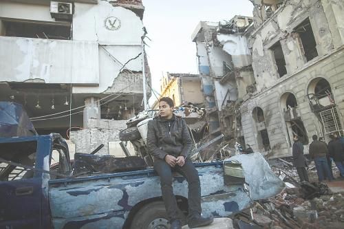 埃及曼蘇拉市警察局24日遭汽車炸彈襲擊，被疑是穆兄會的報復(fù)。圖為一名男子在被炸毀的警察局前。