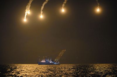 22日，搜救人員在照明彈的光亮下連夜搜救。