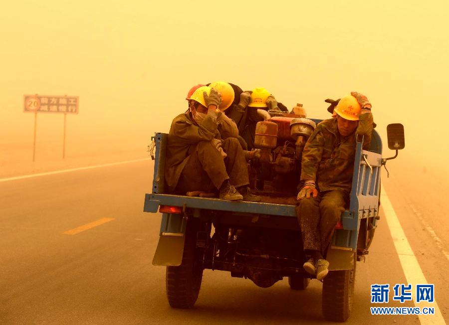 4月23日，一輛拉載公路施工人員的三輪車(chē)在沙塵暴中行駛在酒泉市瓜州縣城郊的公路上。