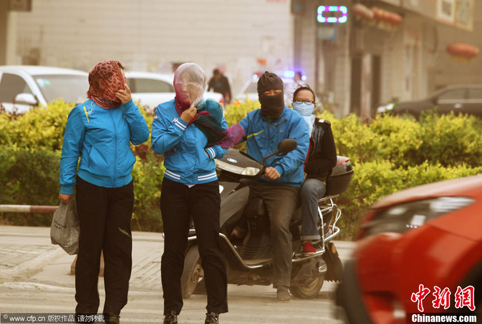 2014年04月23日，新疆維吾爾自治區(qū)吐魯番地區(qū)，市民戴著口罩行走在大風(fēng)沙塵中的吐魯番市街頭。