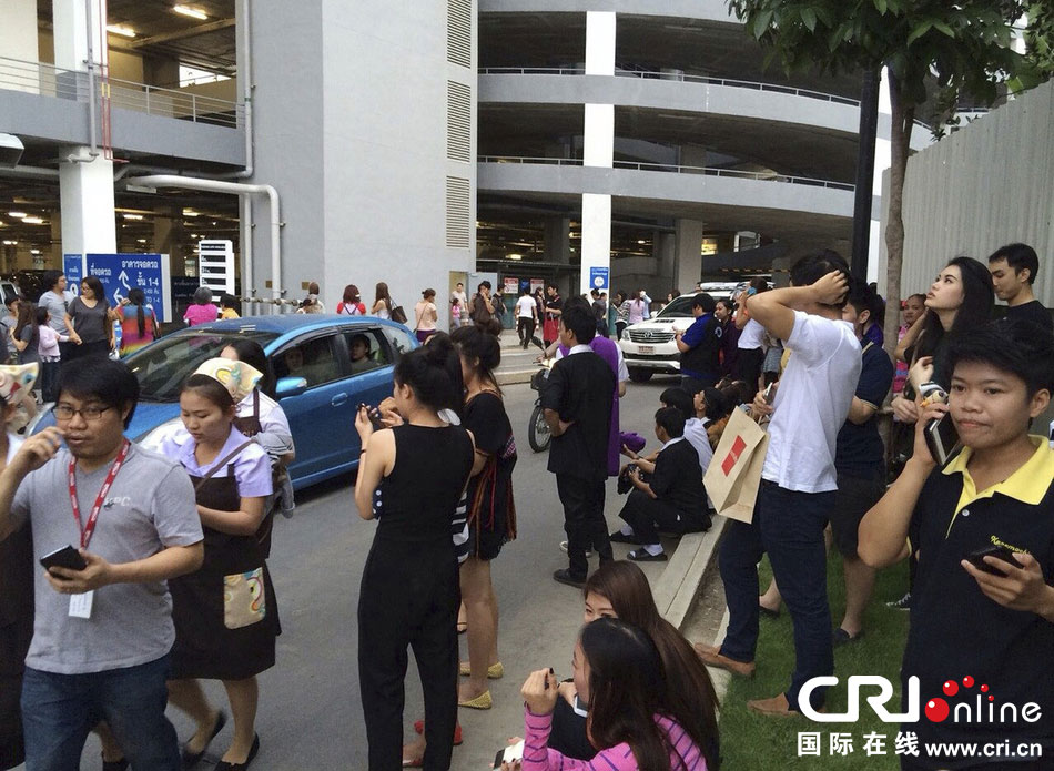 當(dāng)?shù)貢r(shí)間2014年5月5日，泰國清萊，工人們站在一棟大樓外避難。