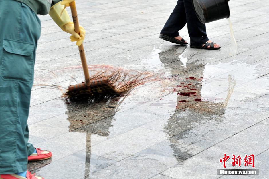 圖為環(huán)衛(wèi)工人在清理案發(fā)地點(diǎn)的血跡。