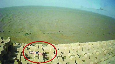 孫正龍游上岸，趴在海邊精疲力盡。