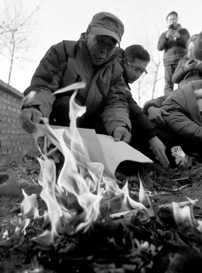 李三仁在兒子墳前焚燒再審無(wú)罪判決文書(shū)的復(fù)印件。新華社發(fā)