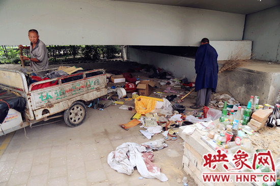 負(fù)責(zé)高架橋下綠化的人員在清理流浪漢留下的垃圾和雜物。