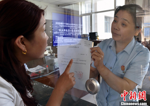 資料圖：2015年5月4日，河北石家莊市橋西區(qū)人民法院立案庭庭長齊燕正在為立案人辦理相關(guān)手續(xù)，完成整個(gè)過程只用了5分鐘。當(dāng)日是立案登記制改革首個(gè)工作日，該院共立案36件，立案率達(dá)到90%。中新社發(fā) 翟羽佳 攝