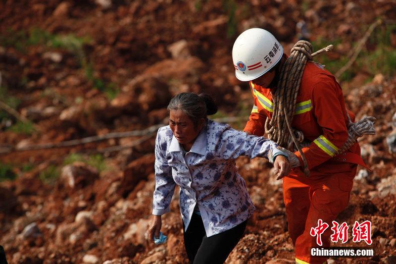 一位消防戰(zhàn)士將一位失去親人的老人扶離滑坡點。