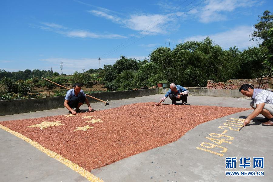 村民馬玉明（左一）用豐收的高粱和玉米在院壩里擺國(guó)旗為祖國(guó)慶生。