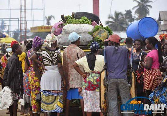 當(dāng)?shù)貢r(shí)間2014年8月14日，利比里亞蒙羅維亞，市場(chǎng)里的商人們圍著一輛汽車。