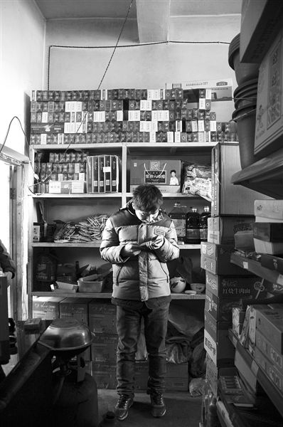 1月21日，周瑋在自家的超市里玩計(jì)算器。