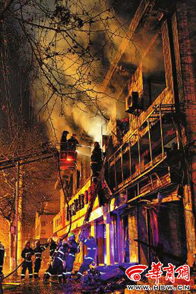 昨日22時10分，西安市豐慶路南小巷南口，消防官兵架梯子登上二樓施救 本組圖片由本報記者 閆文青 攝