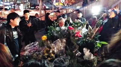 昨晚7時許，三里屯太古里西邊附近一過街天橋旁邊，聞訊而至的網(wǎng)友圍住了賣花老人，爭相買花。 網(wǎng)友“行者橙子”供圖