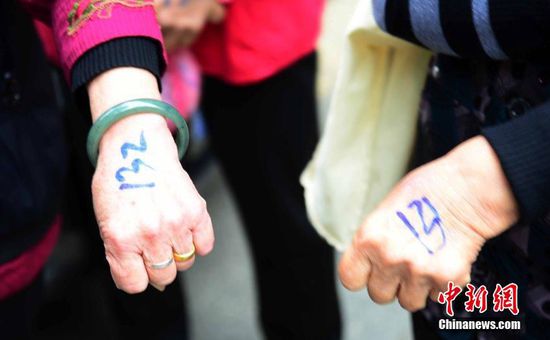 圖為10月28日，在江西九江市一家羊絨皮草服裝服飾博覽會現(xiàn)場，老人們正在頂著寒風排隊等待領取10元代金劵。