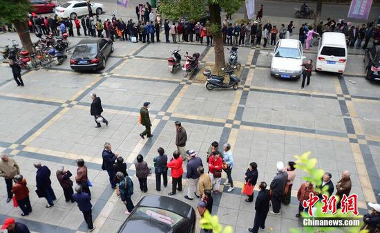 圖為10月28日，在江西九江市一家羊絨皮草服裝服飾博覽會現(xiàn)場，老人們正在頂著寒風排隊等待領取10元代金劵。