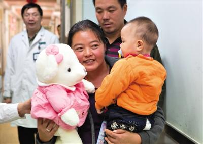 昨日上午，被扎針女嬰的母親抱著孩子和醫(yī)護人員送的玩偶準備出院，院方稱孩子術后恢復良好。記者 高瑋 攝